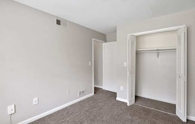 an empty bedroom with a closet and an open door