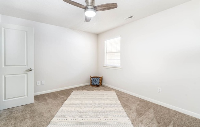 an empty living room with a ceiling fan and a rug