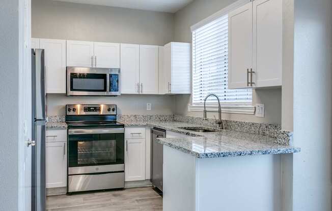 A kitchen with a granite countertop and stainless steel appliances.