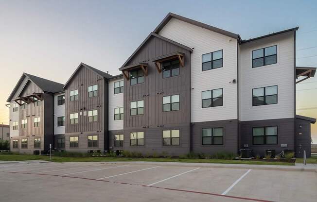 a large apartment building with a parking lot in front of it