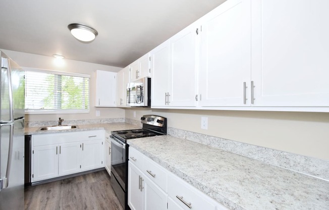 a kitchen with white cabinets and stainless steel appliances