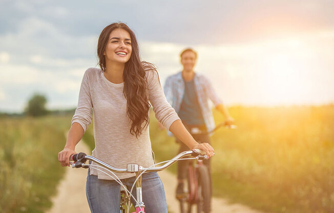 a woman riding a bike with a man in the background at Brownstones at Palisade Park Townhomes, Broomfield, 80023