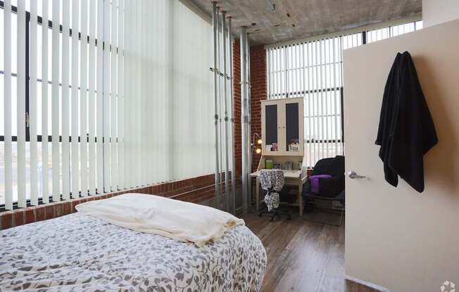 A bedroom with a bed, a chair, and a coat hanging on the wall.