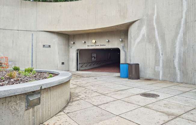 A concrete tunnel entrance with a blue trash can in front.