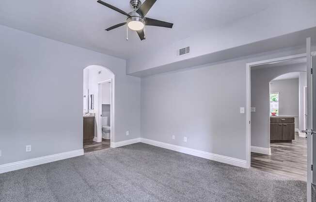 A room with a ceiling fan and carpeted floor.