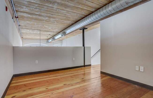 an empty room with a wood floor and white walls