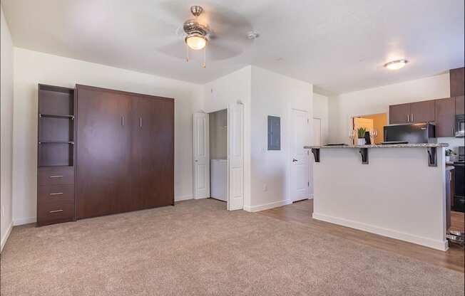 A spacious living room with a ceiling fan and a kitchen area with a microwave and oven at Riverplace Apartment Homes, Independence, OR