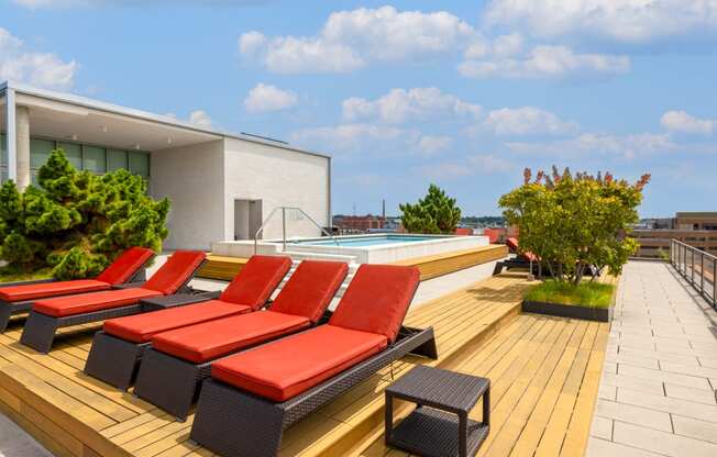 a row of red lounge chairs on a wooden deck next to a pool