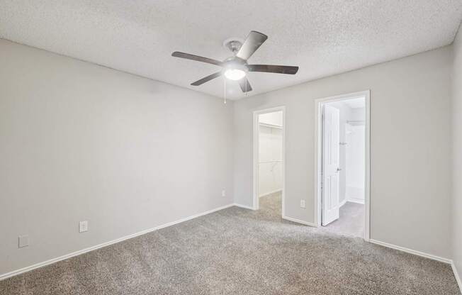 A room with a ceiling fan and carpeted floor.