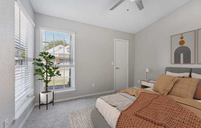 a bedroom with a bed and two windows and a ceiling fan