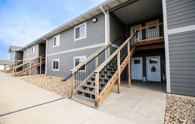 A grey building with a wooden staircase leading to the entrance.