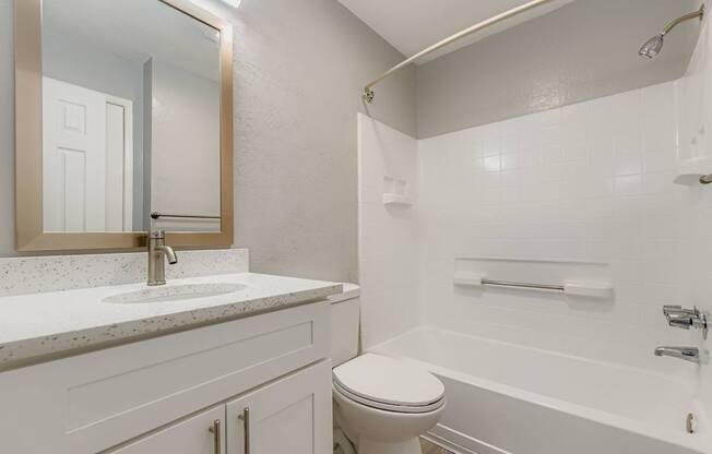 A white bathroom with a toilet, sink, and bathtub.