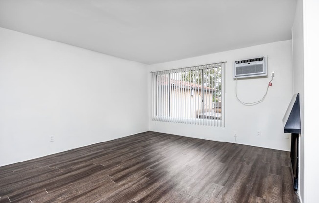 an empty living room with wood flooring and a window