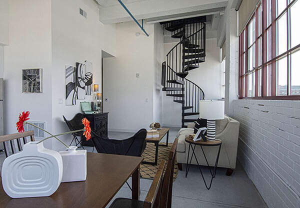 Steelcote Lofts dining/living room area with polished concrete floors, white exposed brick walls and black spiral staircase at Steelcote Square, St. Louis, MO