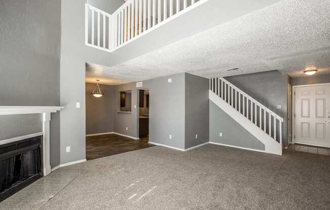 A spacious living room with a fireplace and a staircase.