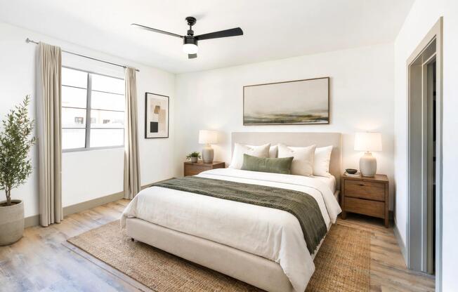 A spacious primary bedroom with wood-style flooring, ceiling fan, and generous natural light for a comfortable, everyday retreat.