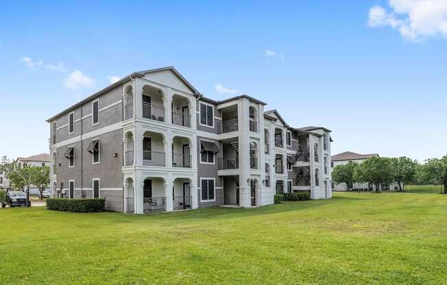 A large, grey apartment building with multiple balconies and doors.