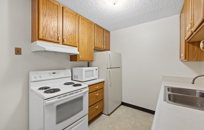 A kitchen with white appliances and wooden cabinets.