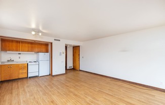 the living room of an empty apartment with wood flooring and a kitchen