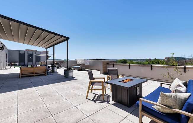 A patio with a table, chairs, and a fire pit.