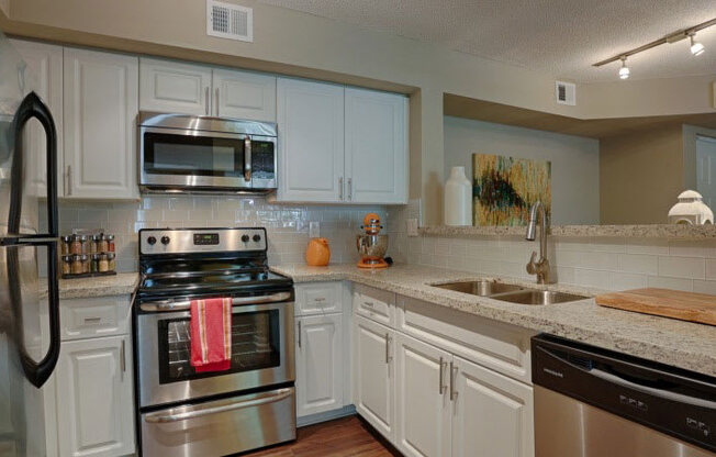 A kitchen with white cabinets and stainless steel appliances.
