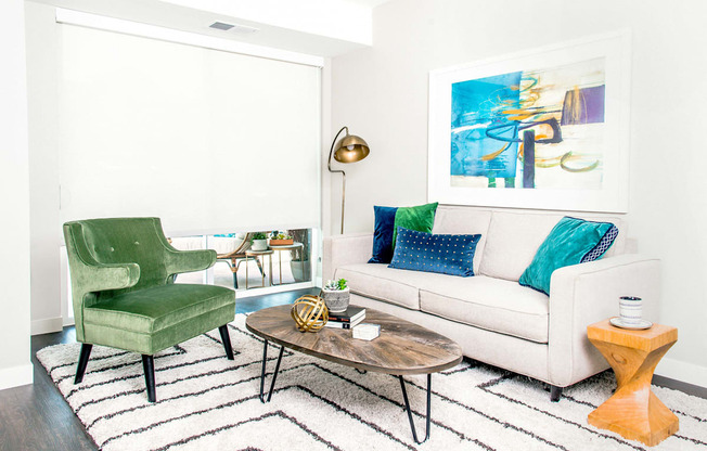 Living room with stain-resistant flooring, showcasing a sliding door leading to a charming patio. Floor-to-ceiling blinds adorn the windows, offering both style and functionality.