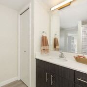 Bathroom with dark vanity cabinets, over sink mirror, and lighting bar at Arabella Apartment Homes, Shoreline