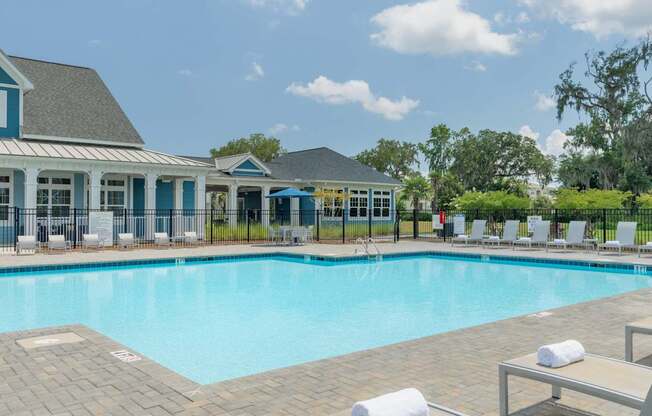 A swimming pool surrounded by lounge chairs and a building with blue trim.