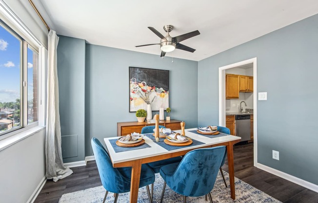 A dining room with a table set for two and a ceiling fan.