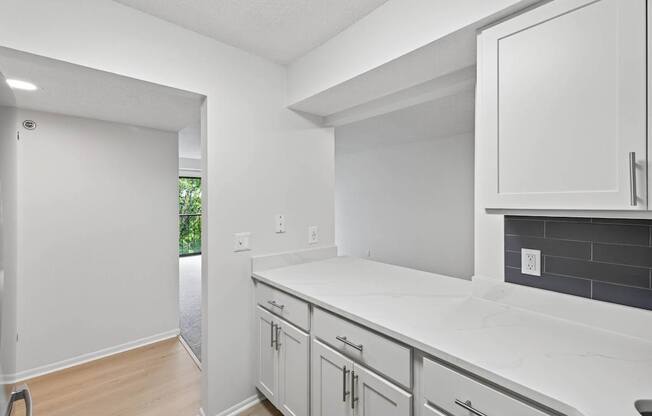 A kitchen with white cabinets and a white counter top.