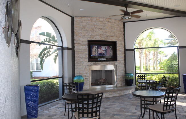 Outdoor lounge with fireplace, TV, and tables and chairs in Orlando, FL 32827