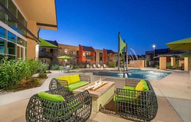 Lounging chairs by outdoor fire in front of resort-style pool at Tempe, AZ apartments