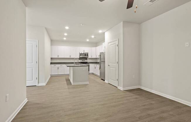 A spacious kitchen with white cabinets and a wooden floor.