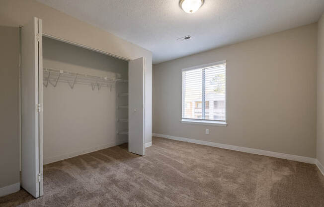 A room with a carpeted floor and a window with blinds.