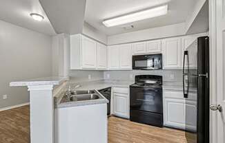 A kitchen with black appliances and white cabinets.