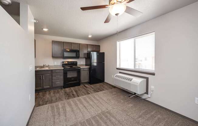 A well-lit, empty room with a kitchenette and a window.