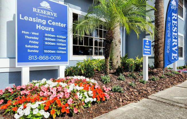 a building with a blue sign and flowers in front of it at Reserve at Temple Terrace, Florida, 33637