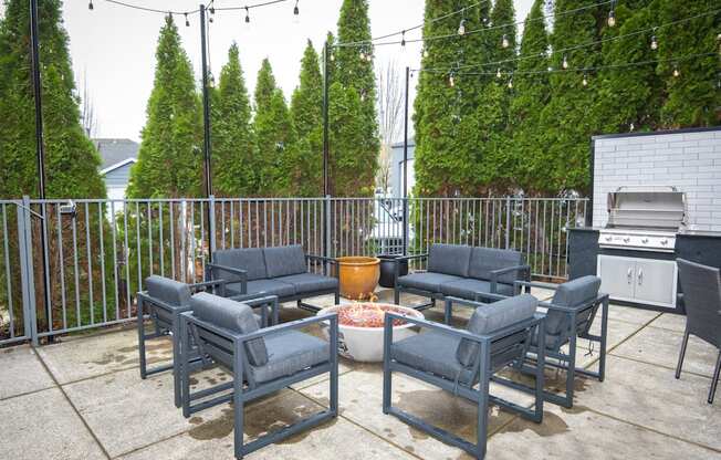 the patio has a gas grill and chairs around a fire pit