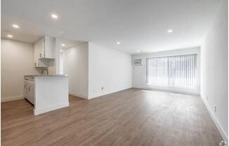 an empty living room and kitchen with a large window