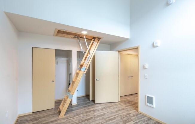 a loft with a ladder in a room with doors