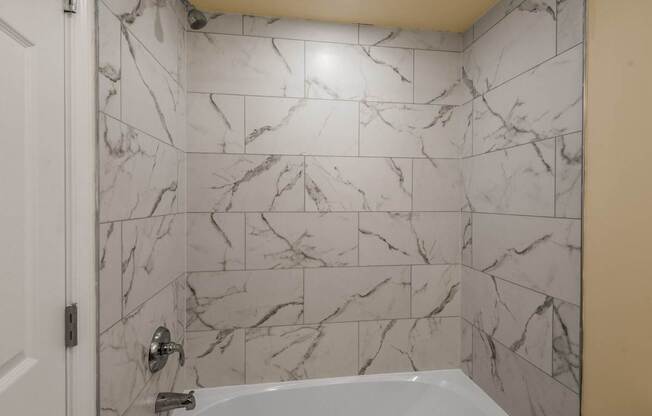 A white bathroom with a marble tile wall.
