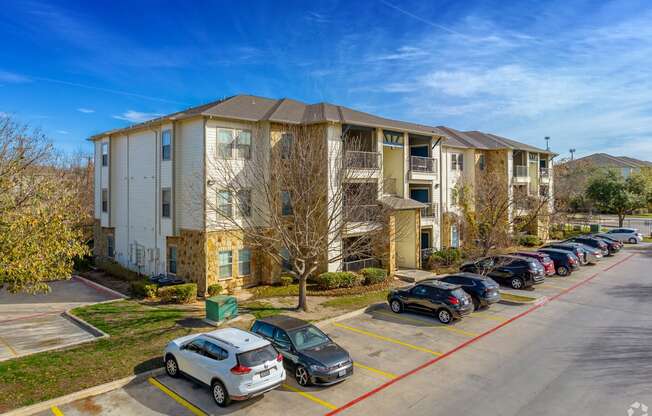 A parking lot with cars and apartment buildings in the background.