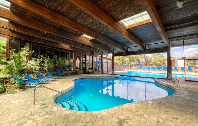 A large indoor swimming pool with a wooden ceiling and tiled floor.