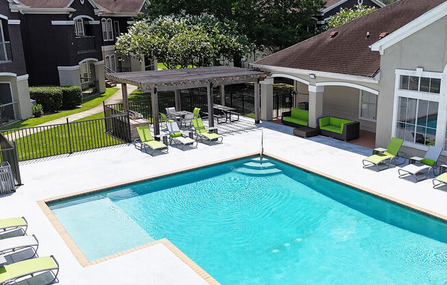 A swimming pool with a deck and lounge chairs.