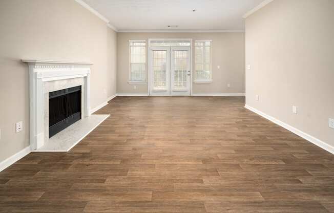 an empty living room with a fireplace and a wooden floor