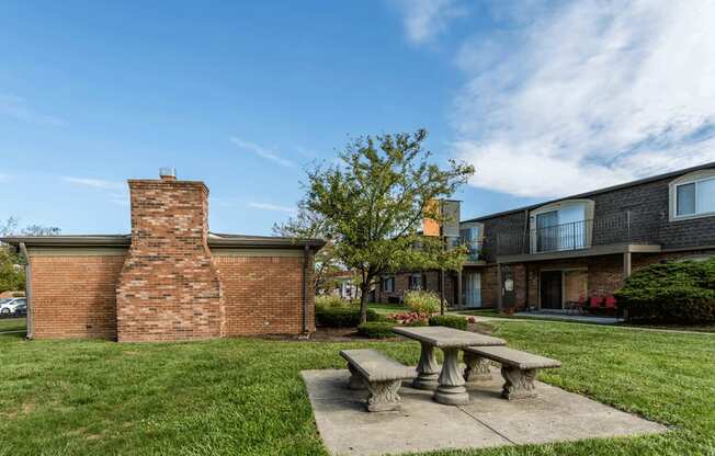 a picnic area with a stone bench in front of a brick building