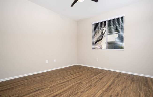 A room with a window covered by blinds and a ceiling fan.