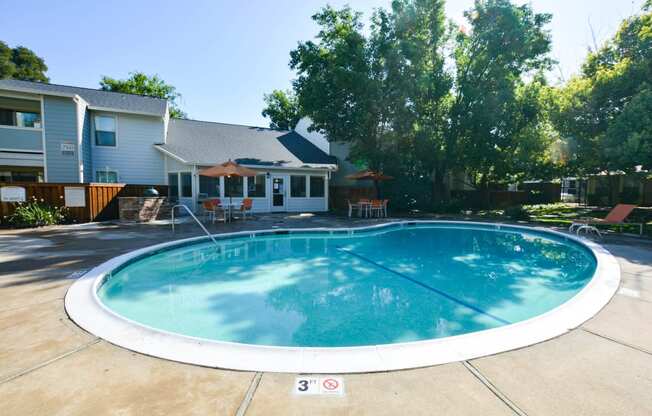 View of community pool, lush shrubbery, private patio/ balcony and exterior of buildings