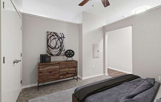 A bedroom with a bed, dresser, and ceiling fan.