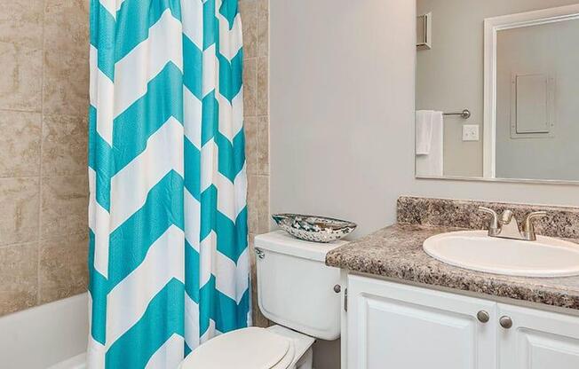 A bathroom with a white toilet, a sink, and a shower curtain. at Bradford Pointe, Georgia, 30909